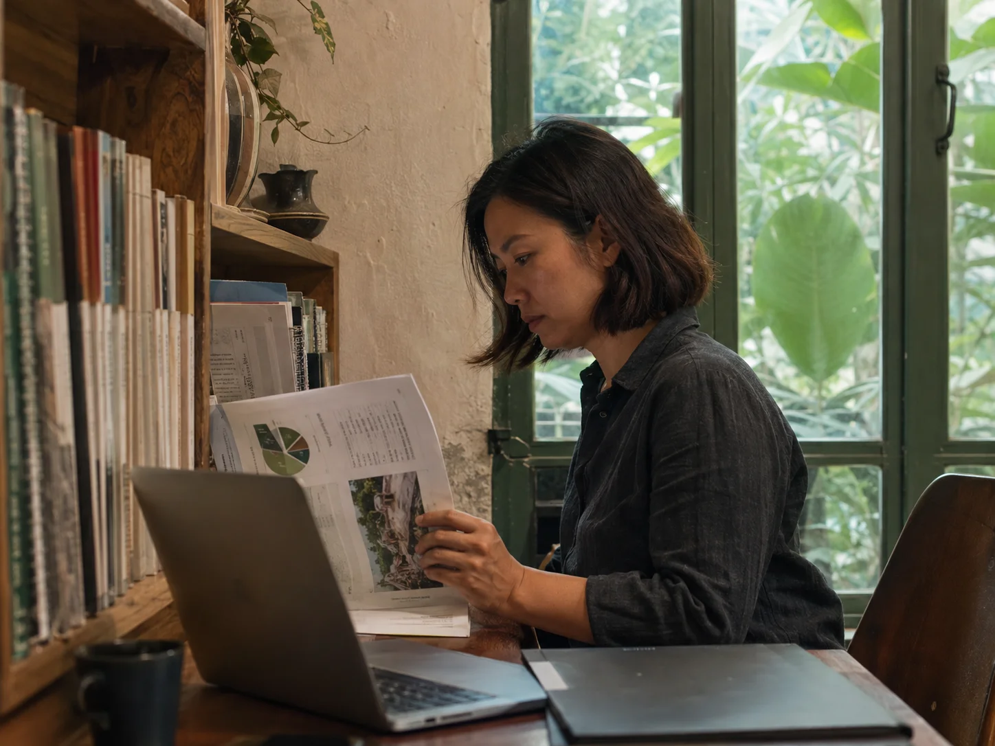 Illustrative scene of a researcher reviewing a report beside a library window