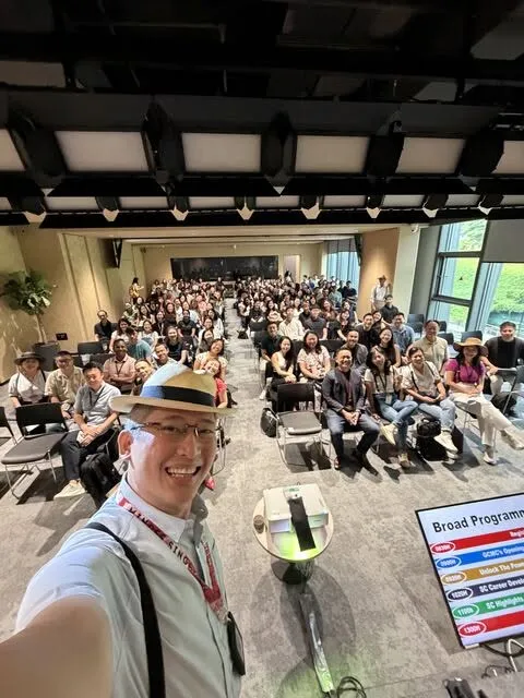 Roy Tan taking a selfie in front of a full hall at a MINDEF strategic communications event